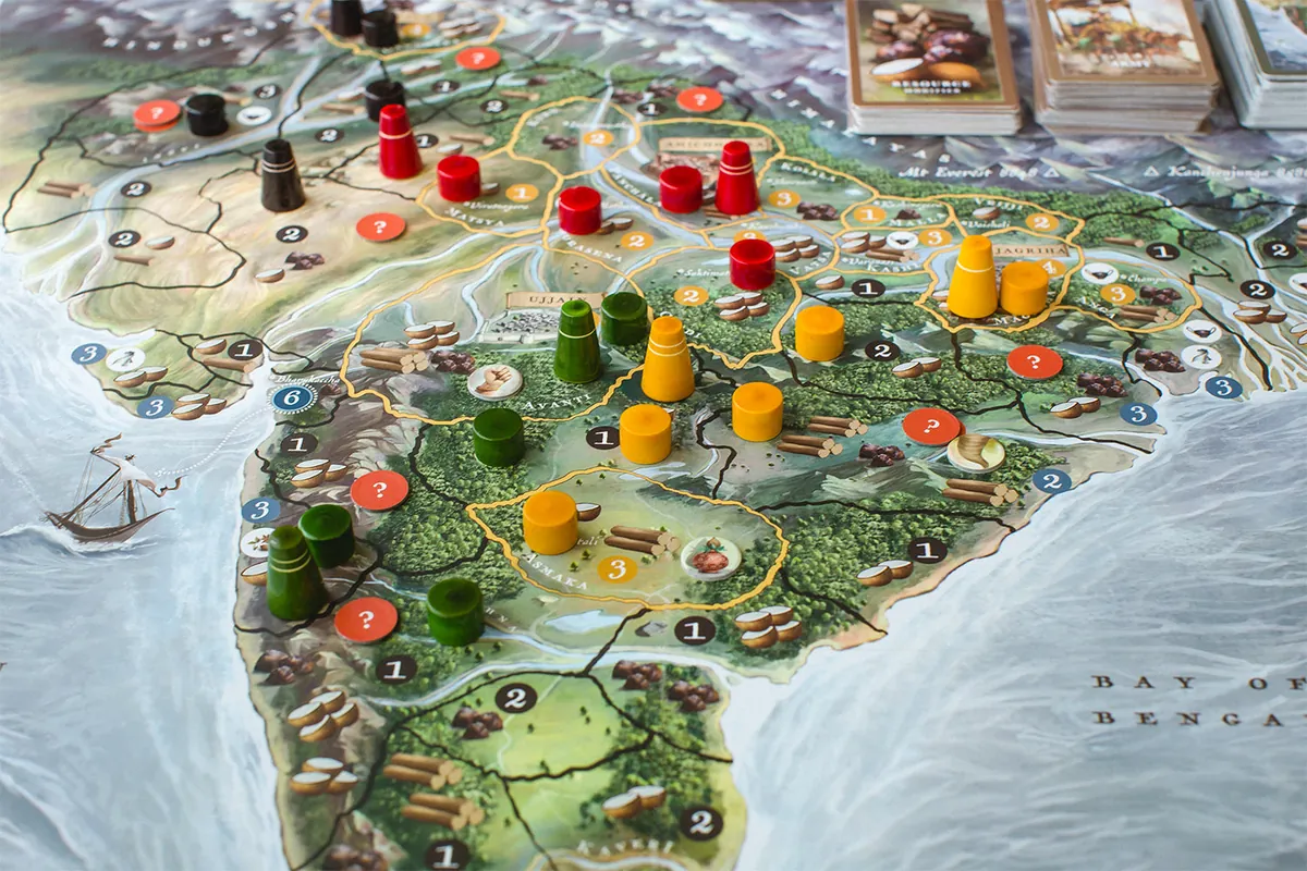 Close-up of the map of northern and central India with tall wooden army pieces and round wooden forts in red, yellow, green and black spread across the regions, plus orange question-mark tokens and resource symbols