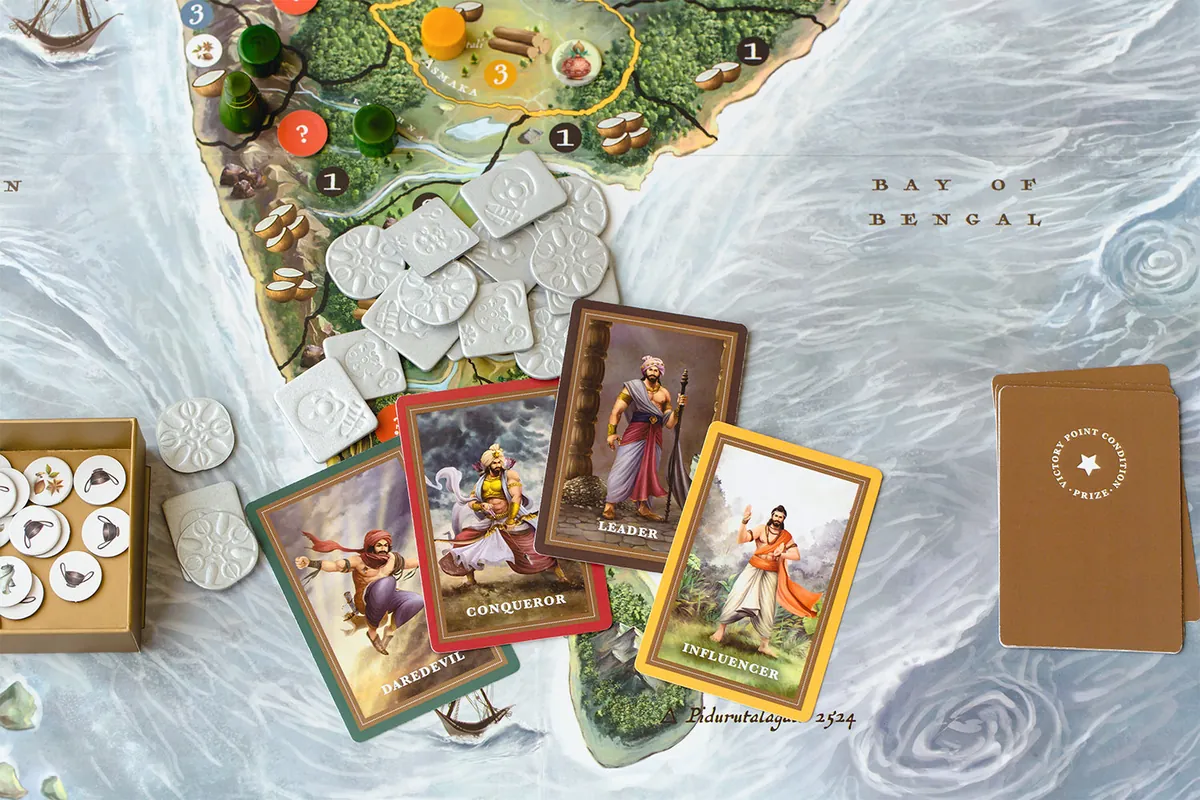 White embossed coins and a tray of round tokens on the southern tip of the map by the Bay of Bengal, with four illustrated personality cards (Daredevil, Conqueror, Leader, Influencer) and the victory-point prize deck