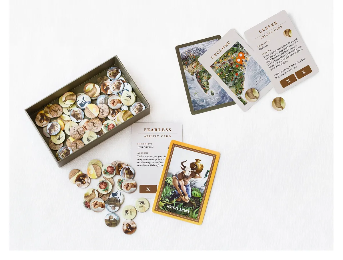 Advanced-game parts on a white table: an open tray of round illustrated event tokens, a Cyclone event card, the back of an event card, and the text sides of the Fearless and Clever ability cards