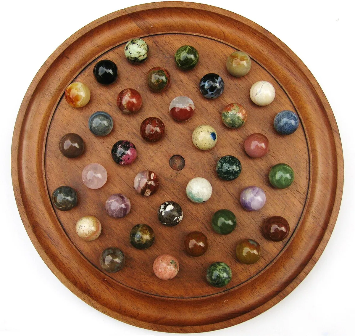A French-style wooden solitaire board filled with stone marbles of different colours