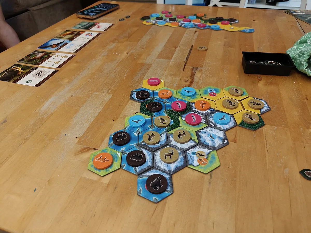 A Cascadia landscape of hexagonal habitat tiles with wildlife tokens on a wooden table