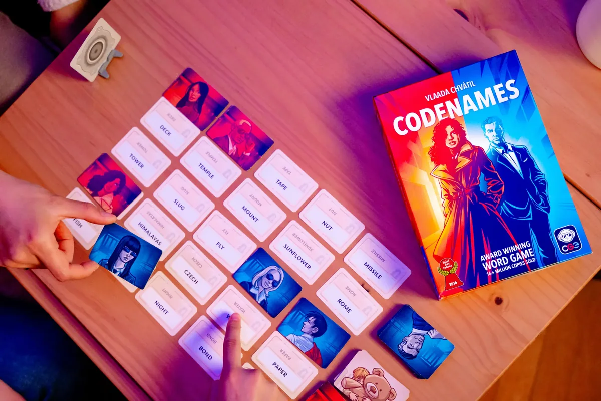 A hand placing a blue agent card on a word card in the grid