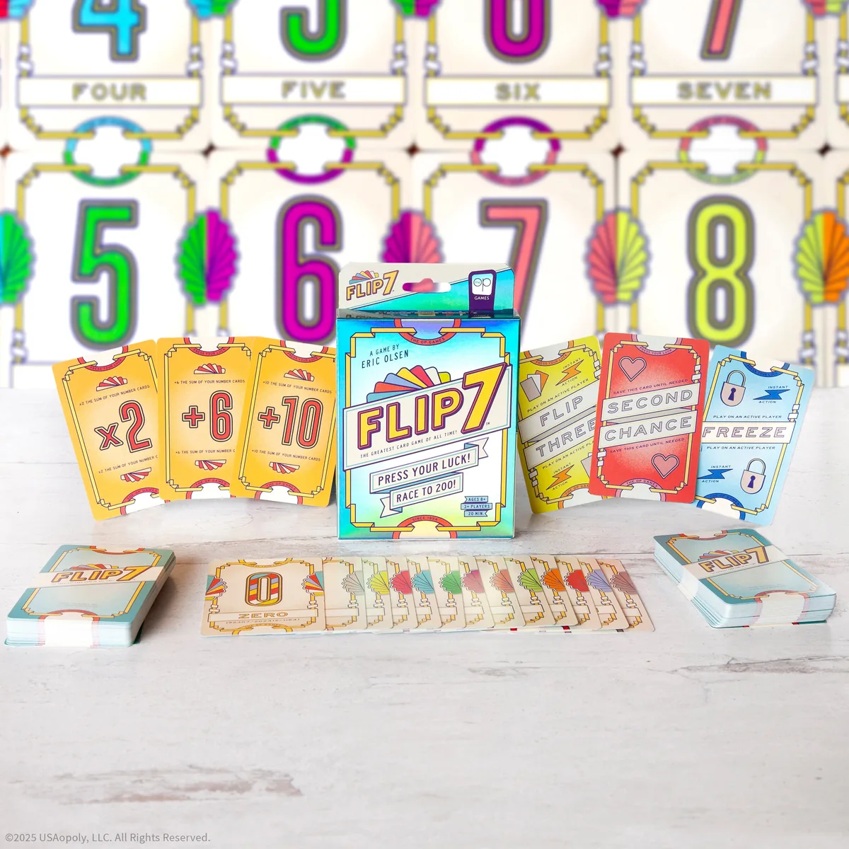 Flip 7 cards spread around the box: big coloured number cards, +2 to +10 and x2 modifier cards, and Freeze, Flip Three and Second Chance action cards