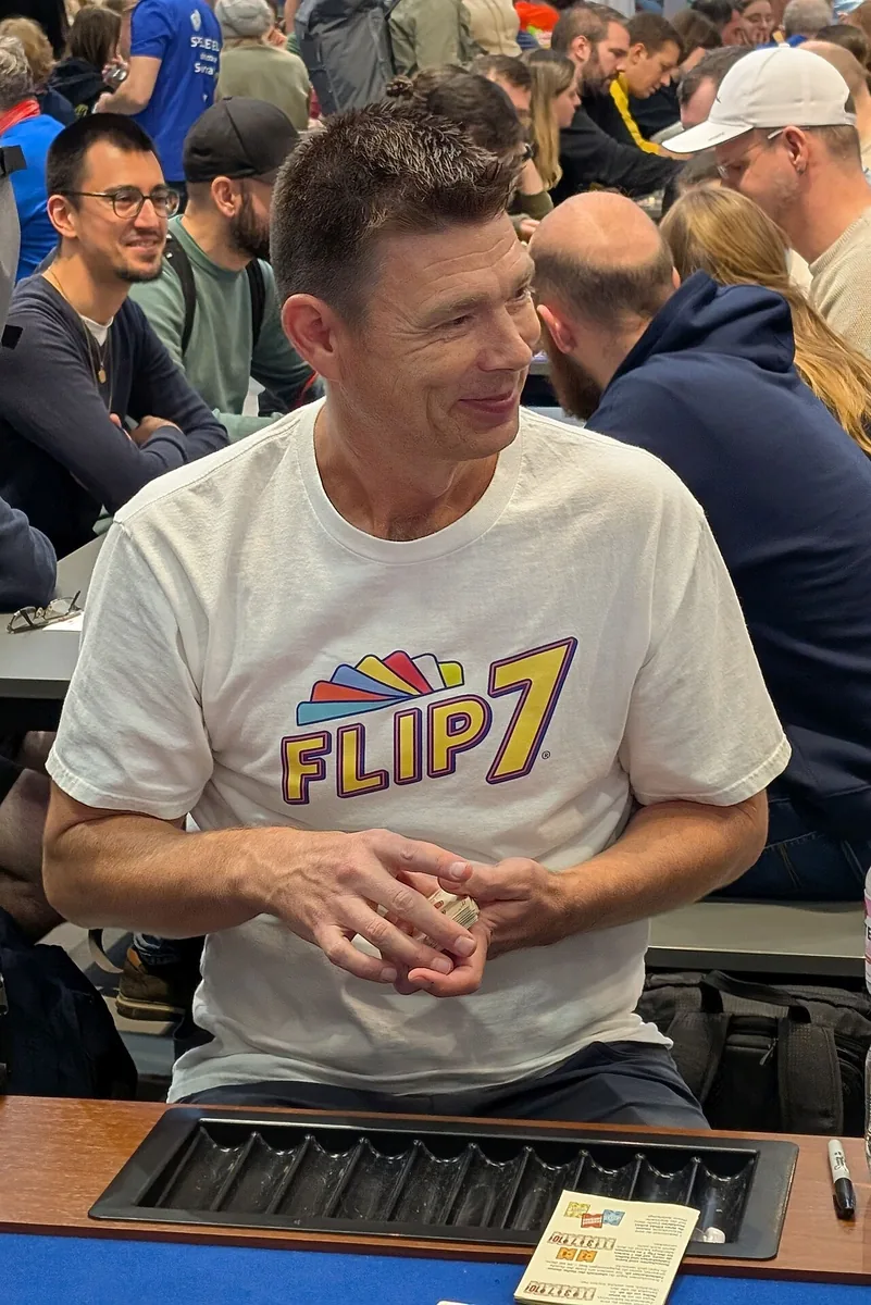 Designer Eric Olsen in a Flip 7 T-shirt at a games table at the SPIEL fair in Essen