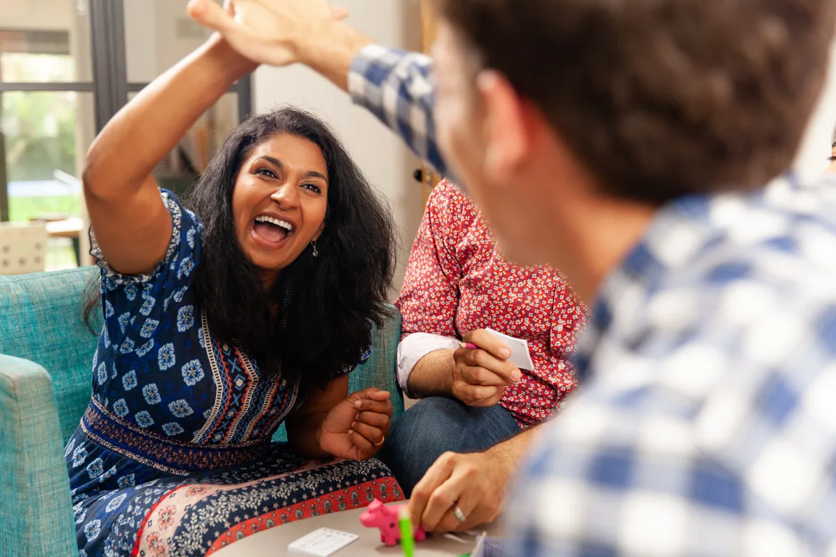 A woman laughing and high-fiving another player across a table