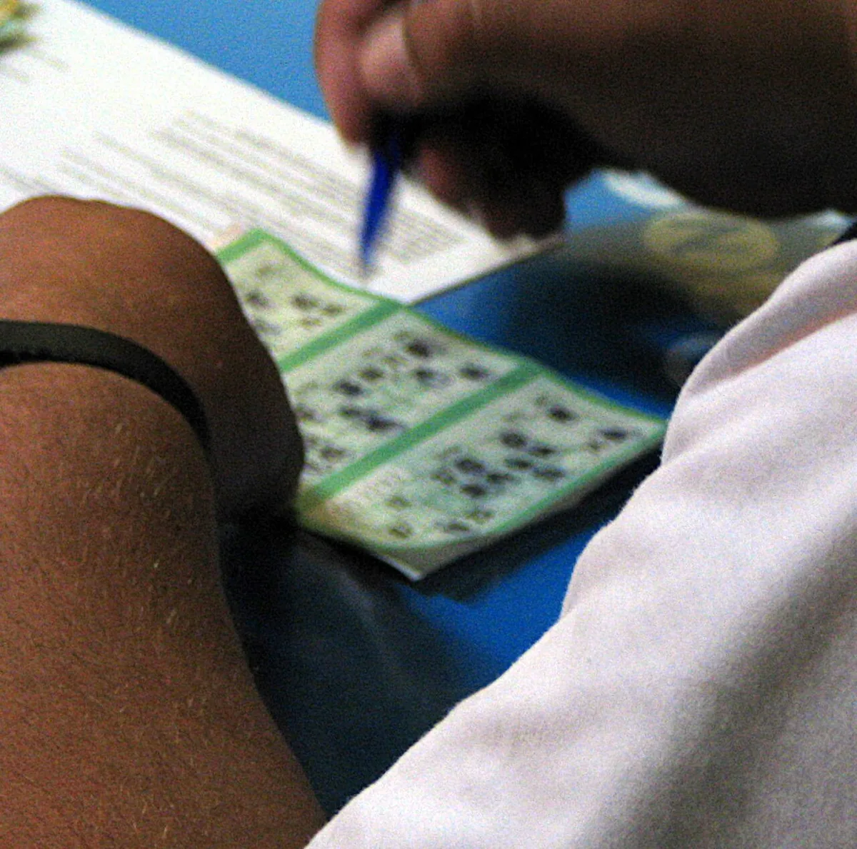A hand marking a tombola ticket with a blue pen