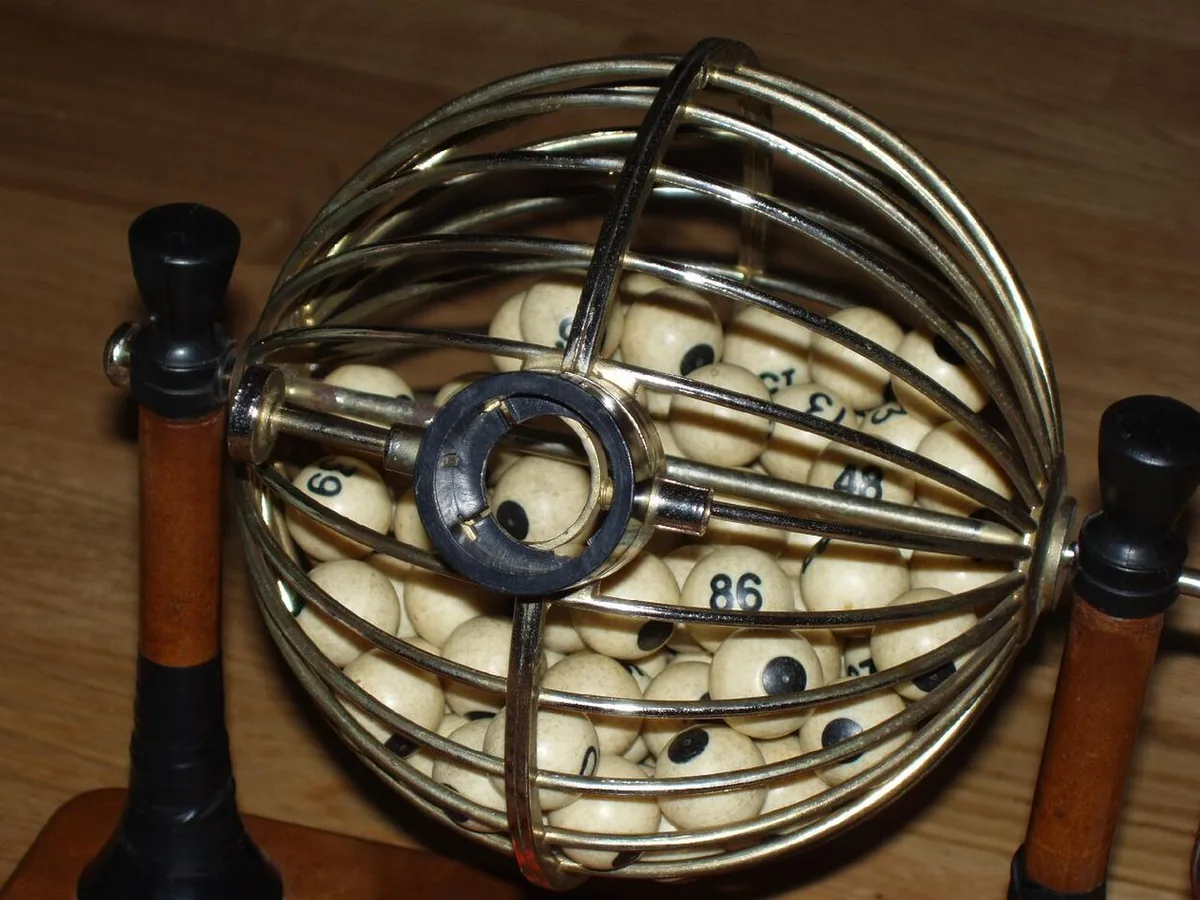 A brass wire ball cage on a stand, used to draw numbered balls