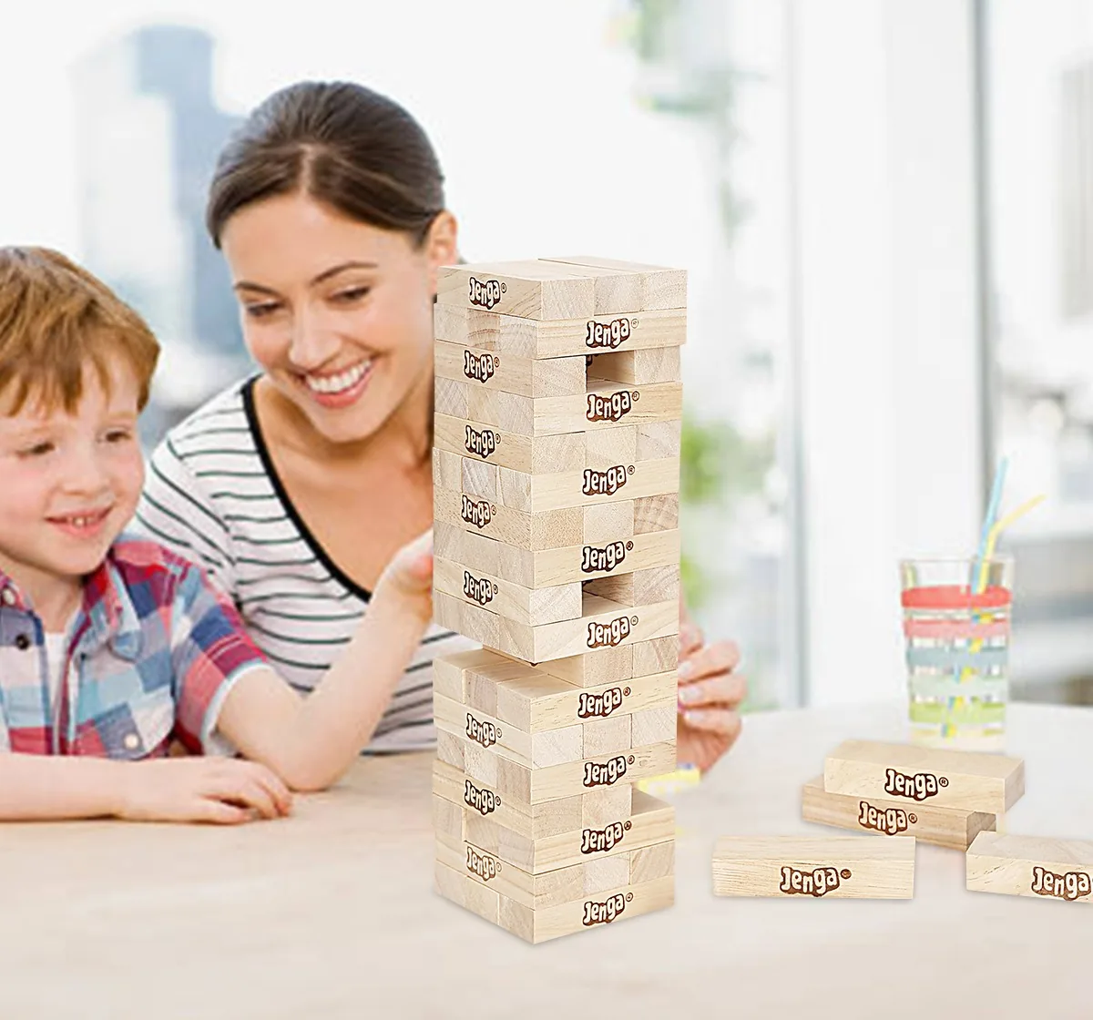 A mother and child at a table watching a Jenga tower with blocks pulled out