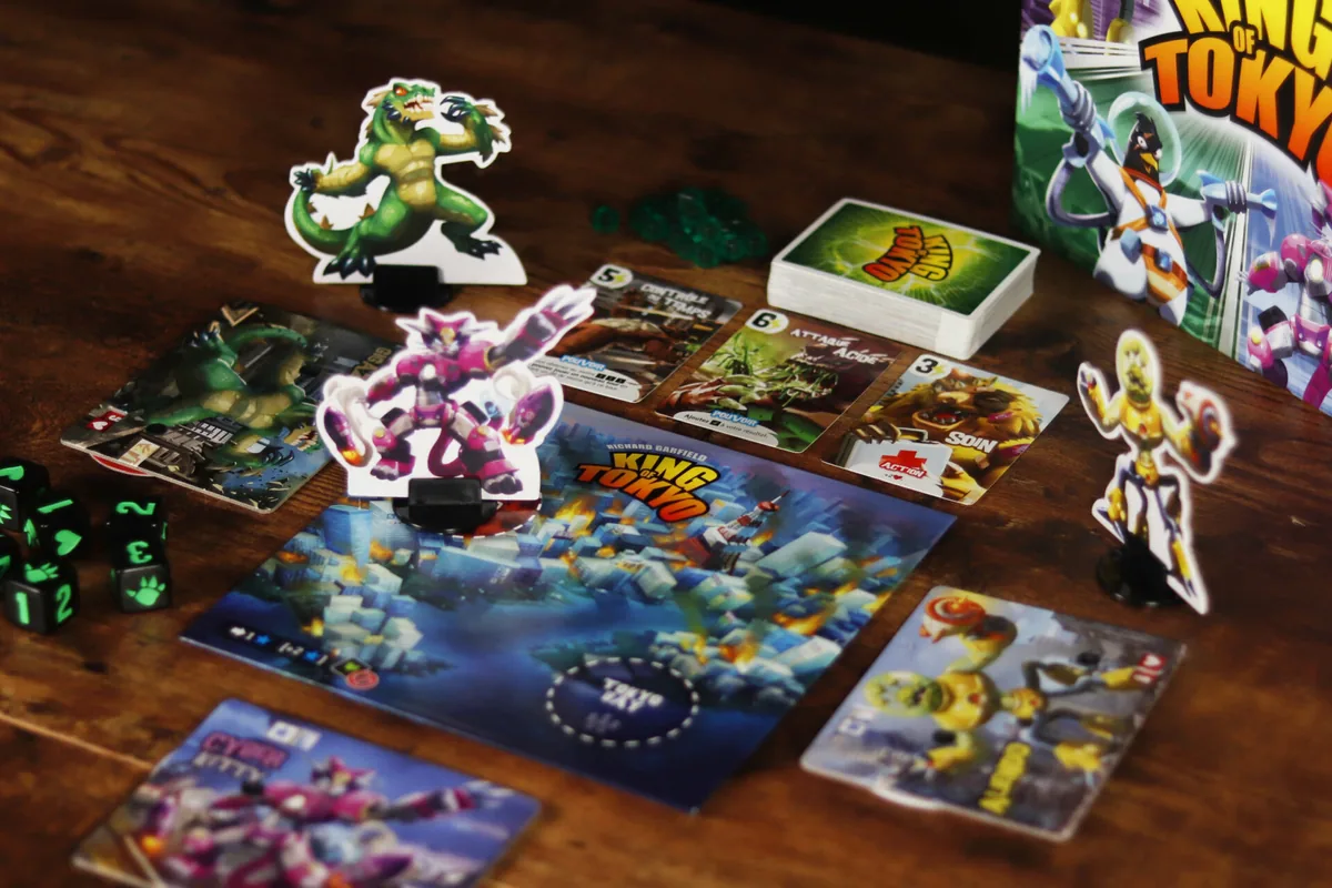 The Tokyo board with monster figures, power cards, green energy cubes and black dice on a wooden table