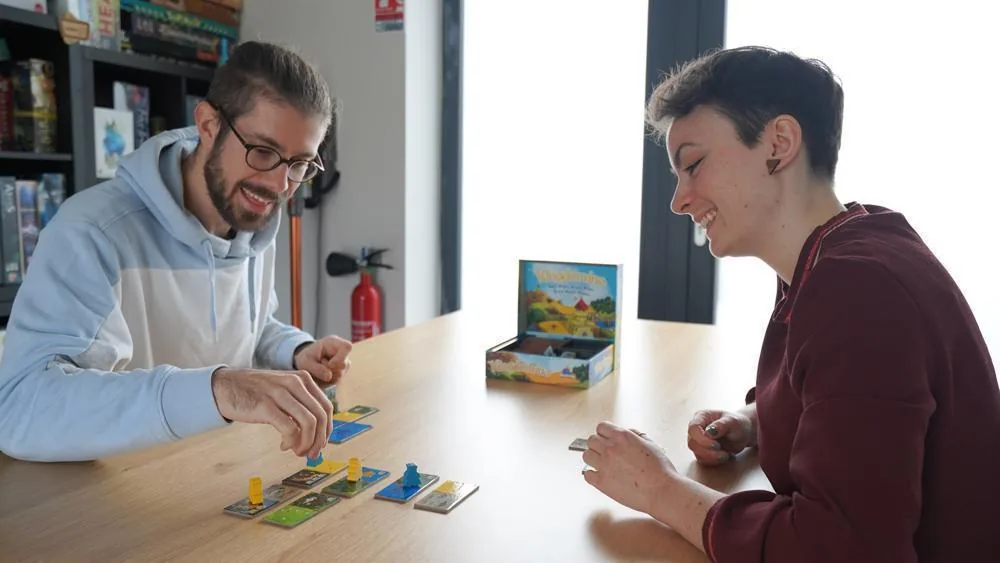 Two players at a table building their kingdoms from domino tiles
