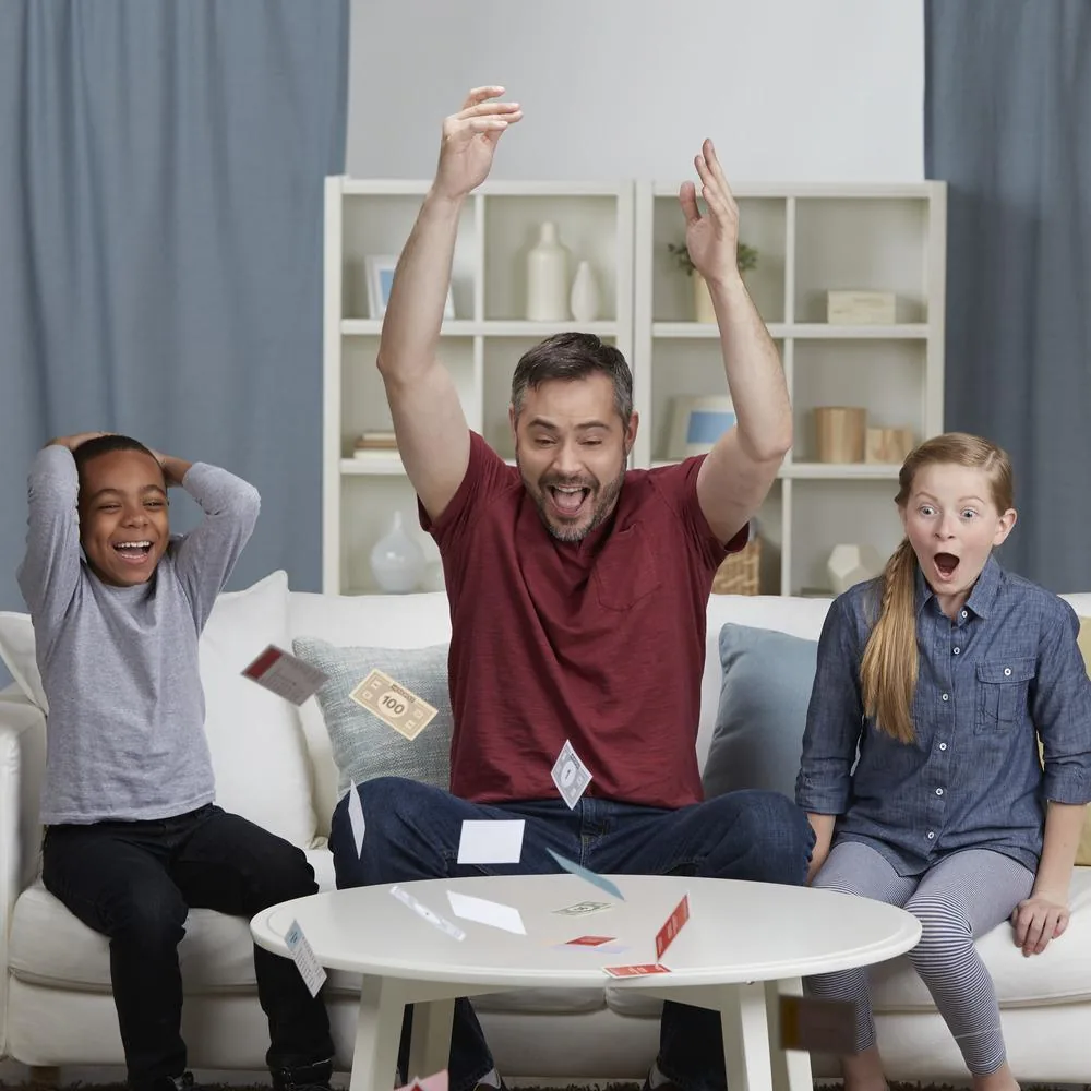 A father and two children cheering on a sofa during a game of Monopoly