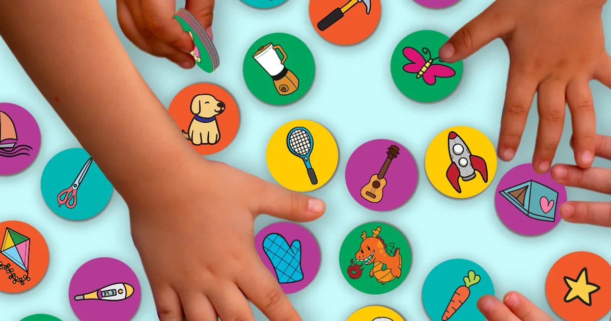 Several hands grabbing round picture tokens spread over a table