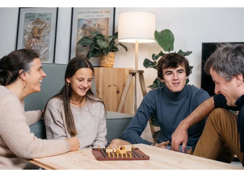 Four people around a coffee table playing a four-player game of Quoridor