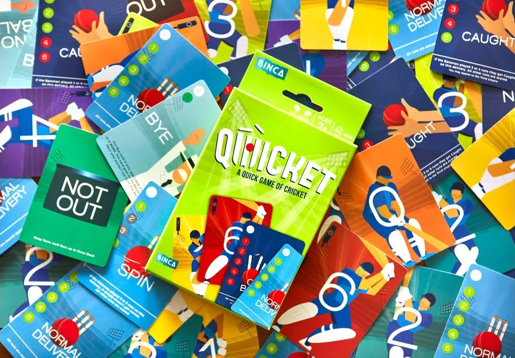 Binca Games' Qwicket pack, lime green, lying on a spread of colourful Qwicket cards (still from Binca's video)