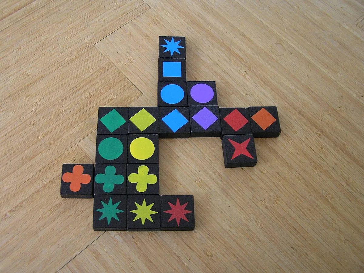 Qwirkle tiles laid in crossing lines of matching colours and shapes