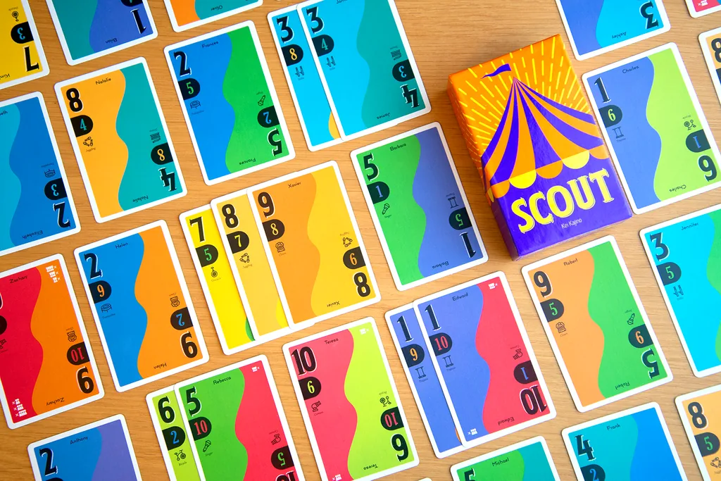 SCOUT cards spread across a wooden table next to the small box, each card showing two numbers