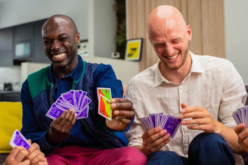 Two friends laughing as they hold their hands of purple-backed SCOUT cards