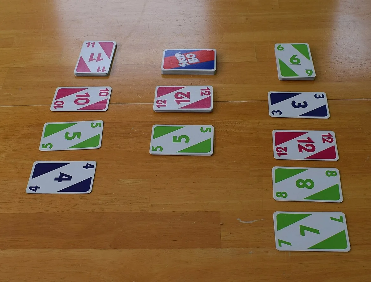 A Skip-Bo game in progress on a wooden table: building piles in the middle and players' discard piles