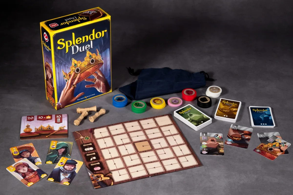 The Splendor Duel box with its board, gem tokens, card decks, cloth bag and privilege scrolls laid out on a grey table