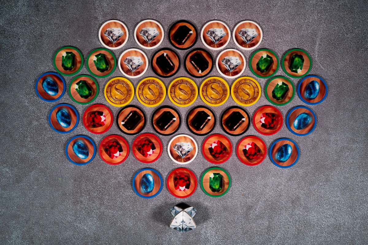 Gem tokens arranged in a fan: white diamonds, blue sapphires, green emeralds, red rubies, black onyx and gold