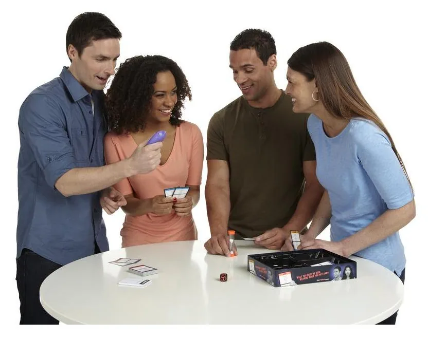 Four young adults huddled around a table, one reading a Taboo card