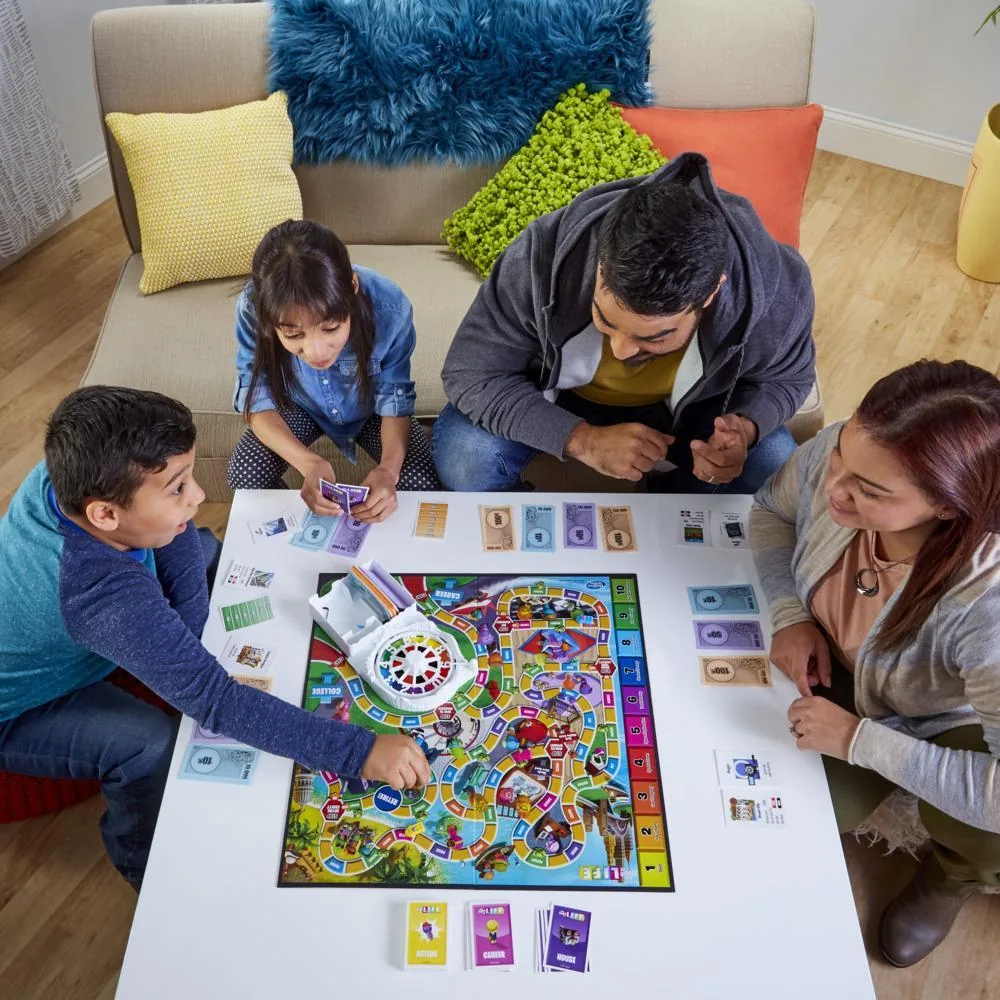 A family of four playing The Game of Life on a white table in a living room