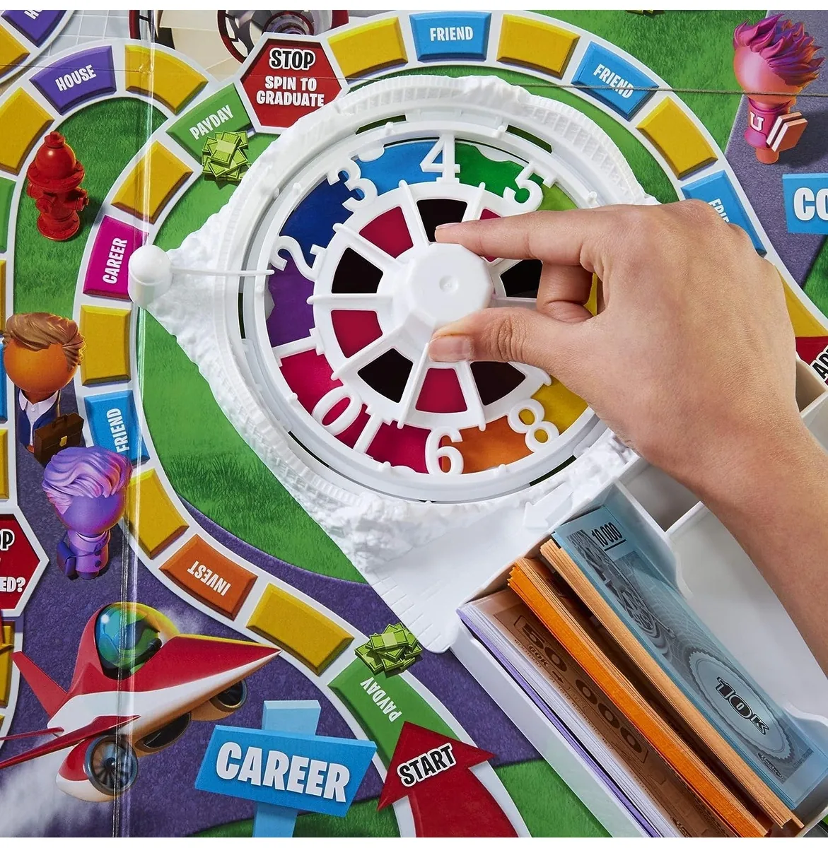 A hand flicking the spinner in the middle of the board