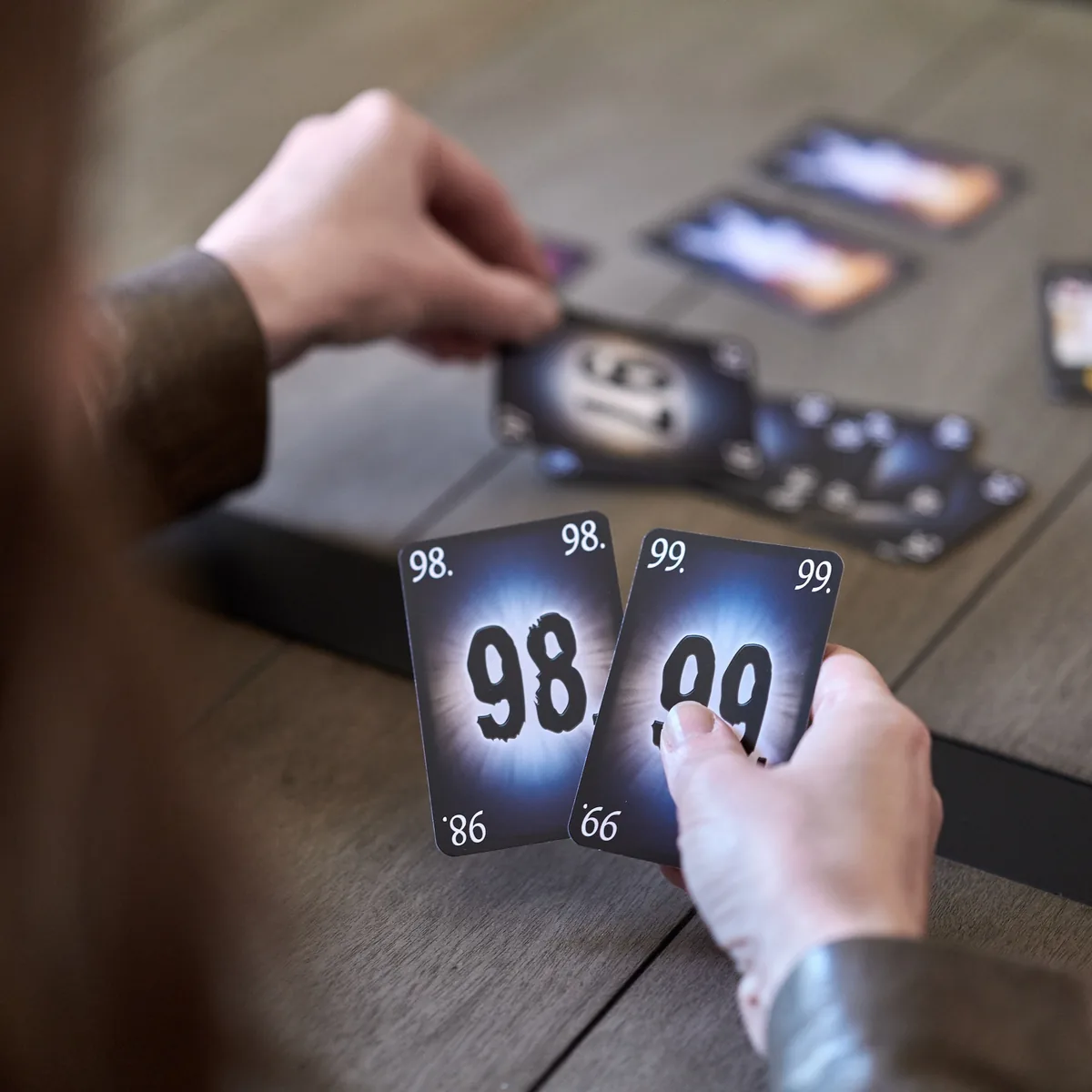 A player holding the 98 and 99 cards above the table