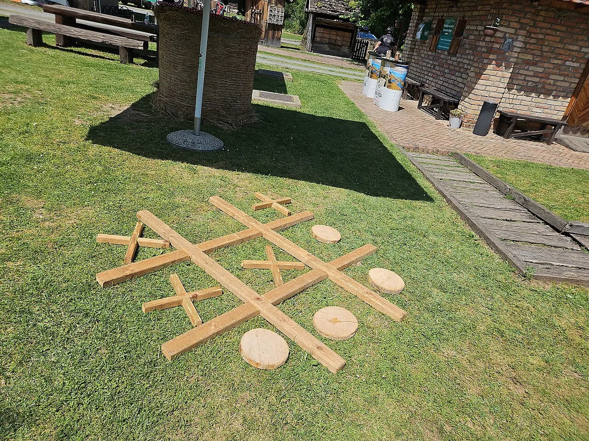 A giant tic-tac-toe made of wooden planks and round wooden discs on a lawn