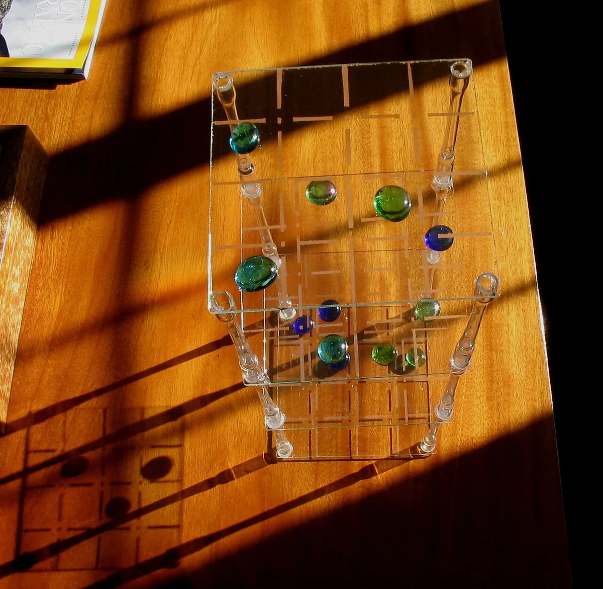 A clear acrylic 3D tic-tac-toe with stacked grids and glass marbles