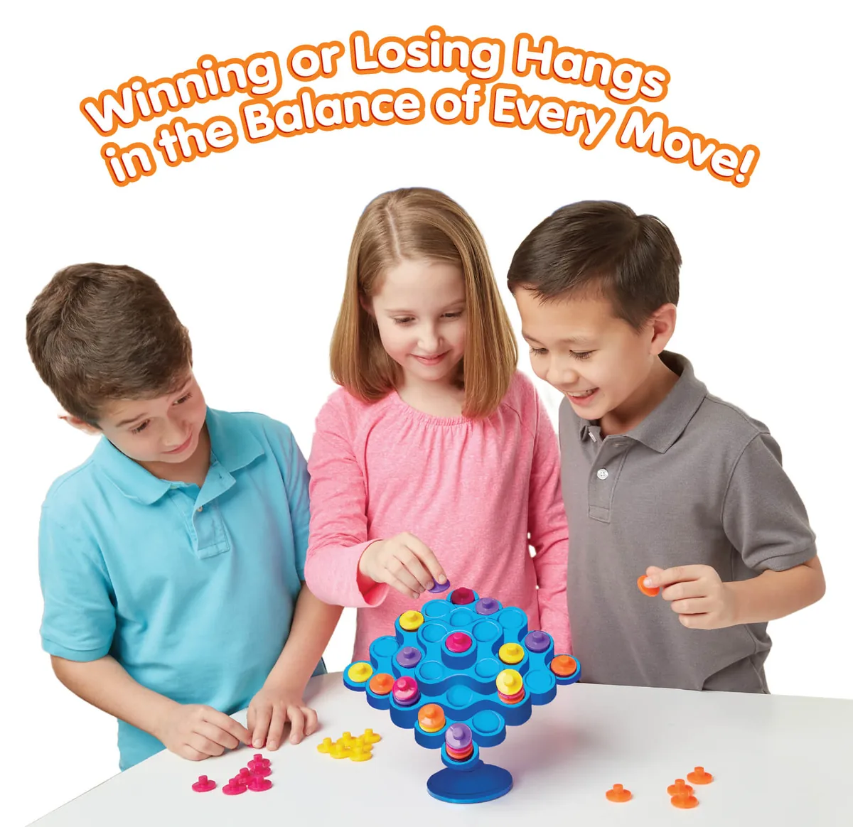 Three children around a Topple tower, one placing a piece while the others watch