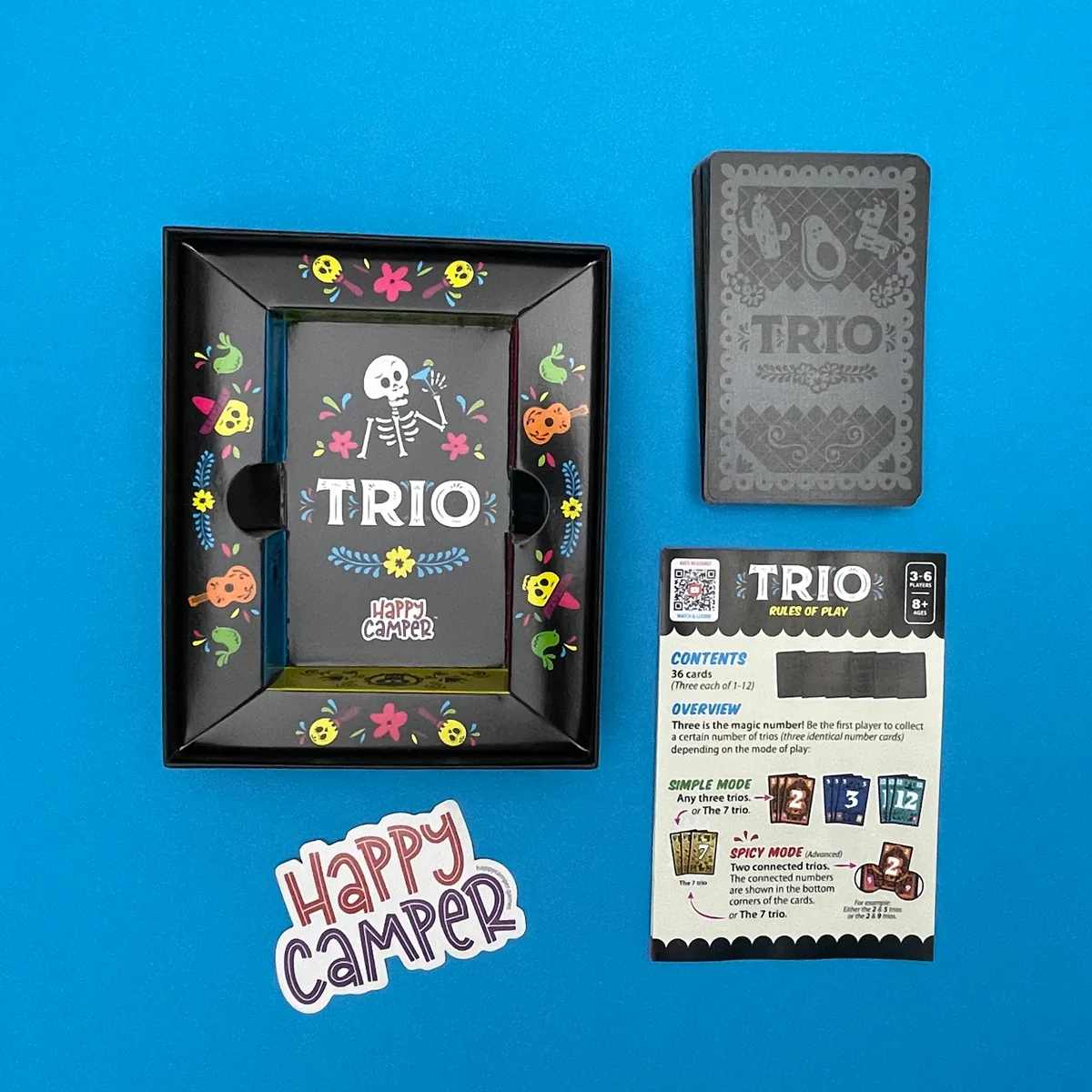 An open Trio box with its card tray, the deck of cards and the rules leaflet on a blue background