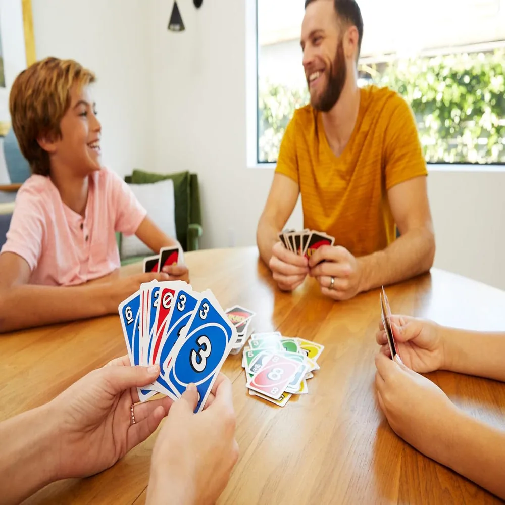 Two players at a wooden table with UNO cards in hand and a discard pile between them