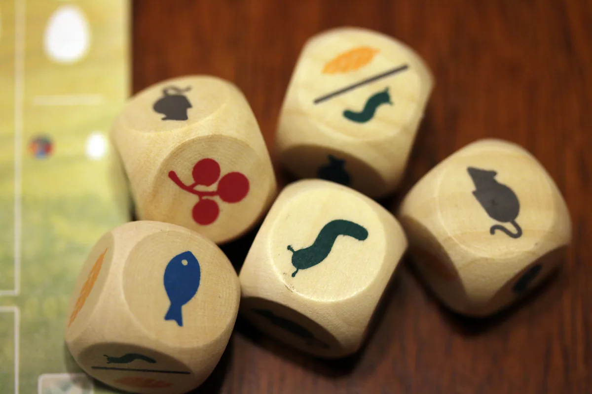 Five wooden food dice showing a mouse, a fish, a worm, cherries and wheat